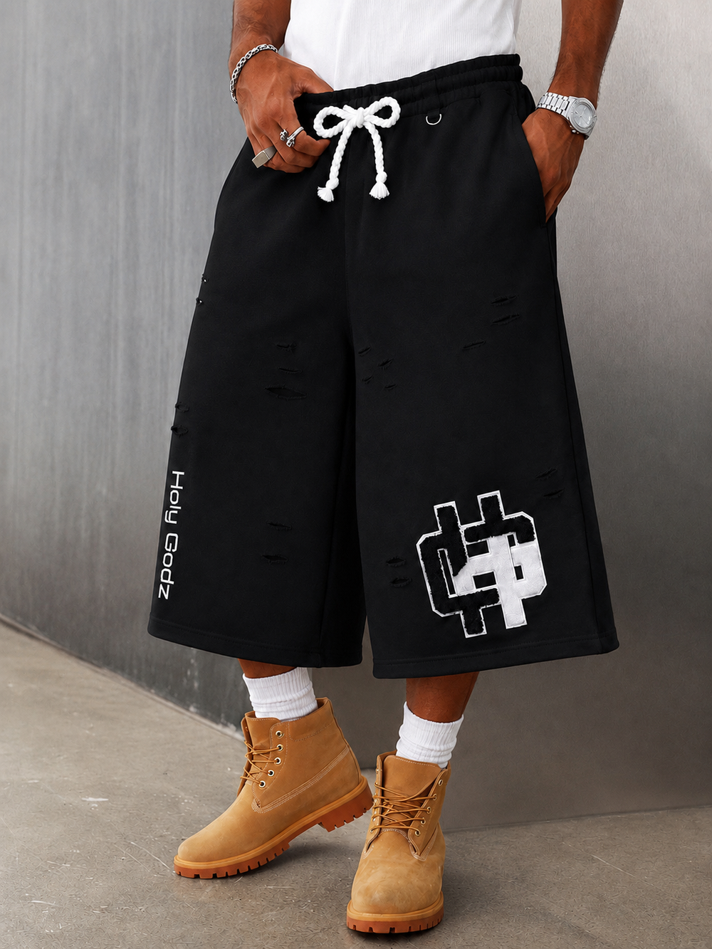 Holy Godz Built Diffrent Shorts in Washed Black worn with boots — boxy 3/4 fit, distressed French terry, chenille HG patch